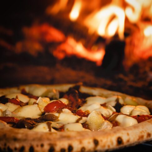 Pizza coming out of wood fired oven